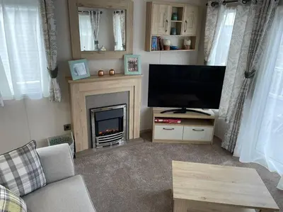 a living room with a television and a fireplace at Mersea Villa in West Mersea