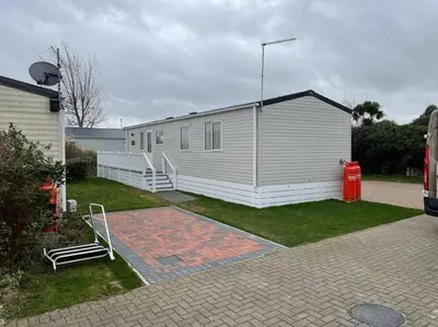 a white building with a red fire hydrant in a yard at Mersea Villa in West Mersea