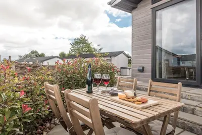 a wooden table with two glasses of wine on a patio at Marshwiggle, Aldeburgh in Aldeburgh
