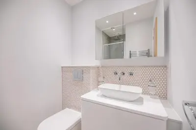 a white bathroom with a sink and a mirror at Ferry Corner Cottage, Sudbourne in Woodbridge