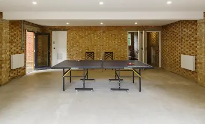 a ping pong table in a room with brick walls at Garden House at Woodhall Estate in Hertford