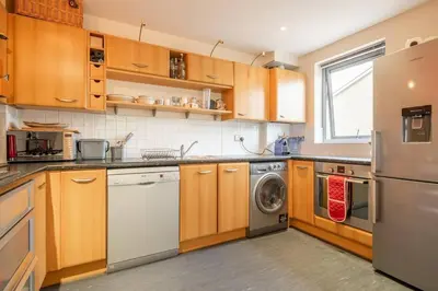 a kitchen with wooden cabinets and a washer and dryer at 2 BR flat next to Train Station & Gated Parking in Cambridge