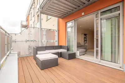 a patio with a couch and a table on a balcony at 2 BR flat next to Train Station & Gated Parking in Cambridge