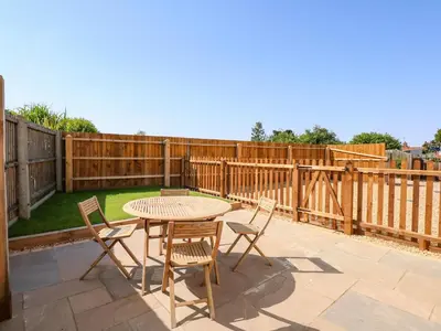a patio with a table and chairs and a fence at Postbox Cottage in Thetford