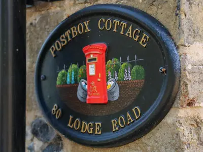 a sign on a wall with a british red telephone pole at Postbox Cottage in Thetford