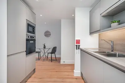 a kitchen with white cabinets and a wooden floor at Citystay Living - Dutch's Corner in Cambridge