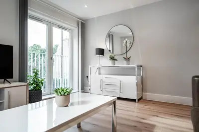 a white living room with a table and a mirror at Citystay Living - Dutch's Corner in Cambridge