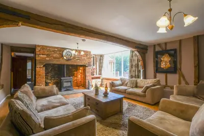 a living room with couches and a fireplace at Moat Barn in Debach