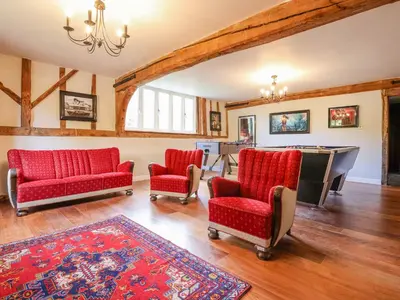 a living room with red chairs and a pool table at Moat Barn in Debach