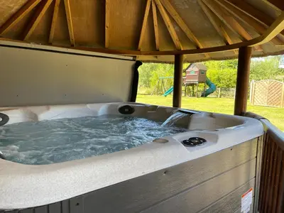 a hot tub in a gazebo with a playground at Moat Barn in Debach