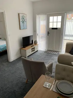 a living room with a table and chairs and a television at The old forge in Graveley