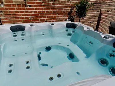 a jacuzzi tub in front of a brick wall at Executive Suite with Private HotTub, Full SkyTV in 600 Year Old Manor House in Saffron Walden