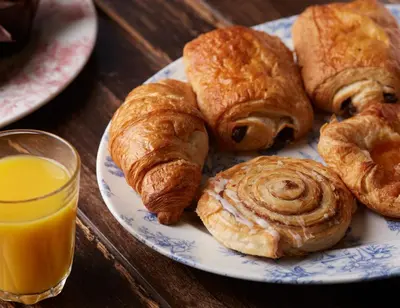 a plate of pastries on a table with a glass of orange juice at Dog and Partridge by Greene King Inns in Bury Saint Edmunds