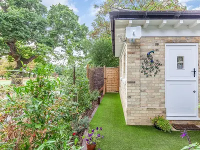 a garden with a white door on a brick building at Peacock On The Pin in Stisted