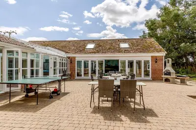 a patio with a ping pong table and chairs at Cottage In Norfolk Sleeps 23 - Private Pool, Fishing Lake, Hot Tub Ref 99008Sc in Hockham