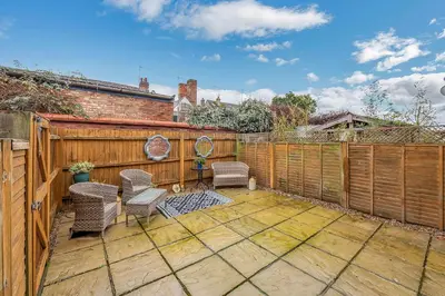 a patio with chairs and a wooden fence at 10 St Edmundsbury Mews in Bury Saint Edmunds