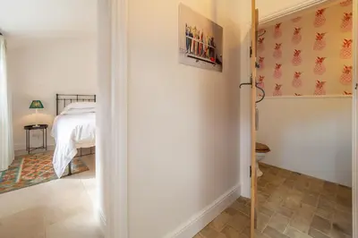 a bedroom with a bed and a door leading to a bathroom at Luxurious rural retreat - Holt Coach House in Sudbury