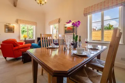 a dining room with a wooden table with wine glasses at Luxurious rural retreat - Holt Coach House in Sudbury