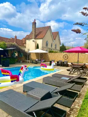 a pool with inflatables and tables and a house at Grade II Listed Farmhouse, Pool, Hot Tub, Games Room, Celebration Hall, Car Park, 10ppl, 45 min from Central London in Stapleford Tawney