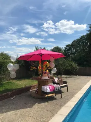 a table with a red umbrella next to a pool at Grade II Listed Farmhouse, Pool, Hot Tub, Games Room, Celebration Hall, Car Park, 10ppl, 45 min from Central London in Stapleford Tawney