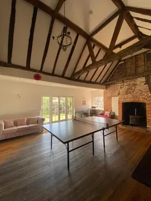 a living room with a table in the middle of it at Grade II Listed Farmhouse, Pool, Hot Tub, Games Room, Celebration Hall, Car Park, 10ppl, 45 min from Central London in Stapleford Tawney
