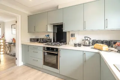 a kitchen with white cabinets and a stove top oven at Stripe Cottage - Aldeburgh Coastal Cottages in Aldeburgh