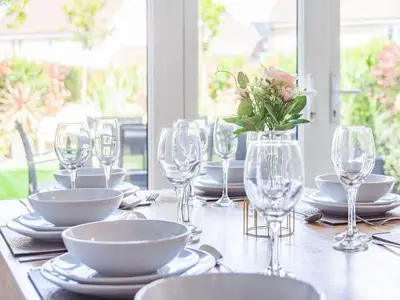 a table with glasses and plates and a vase of flowers at Violet Place in Broomfield