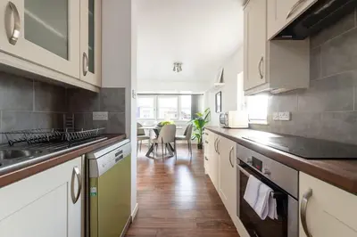 a kitchen with white cabinets and wooden floors and a table at City Center,2 Bedroom Apartment with Parking in Cambridge