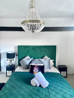 a bedroom with a green bed with towels on it at Farmhouse Retreat with Hot Tub, Pool, Horses, Games Room, Free Car Park, Only 45 min from Oxford Circus in Stapleford Tawney