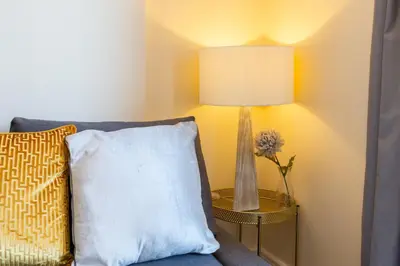 a lamp on a table next to a couch with a pillow at Velvet 1-bedroom penthouse, Clockhouse, Hoddesdon in Hoddesdon