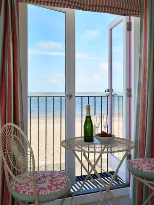 a balcony with a table and chairs and a view of the beach at Magenta - A stunning Seafront house with lovely and uninterrupted Beach Views - Aldeburgh Coastal Cottages in Aldeburgh