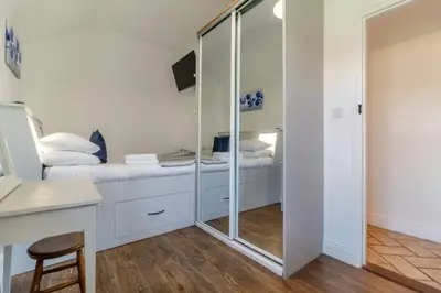 a white room with a bed and a desk and a mirror at Tilly's, a two bedroom holiday retreat with hot tub and views of the pond in Barningham