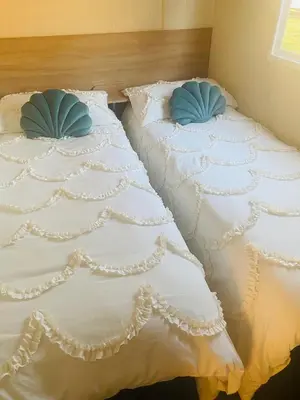 two beds with white sheets and blue pillows at Shell Beach Holiday Home Mersea Coopers Beach in East Mersea