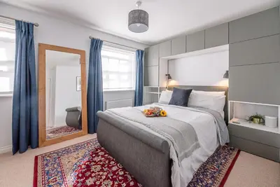 a bedroom with a large bed and a mirror at Martlet Cottage Aldeburgh in Aldeburgh
