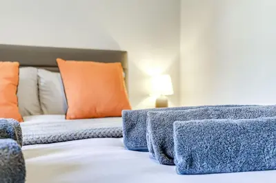 a bed with a blue blanket and orange pillows at The Old Warehouse Ely in Ely