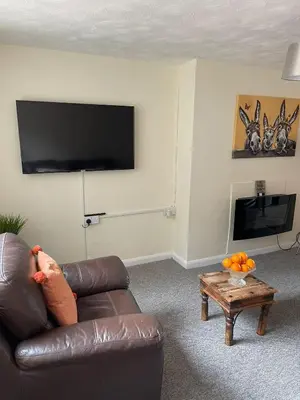 a living room with a brown leather couch and a table at Sea Breeze in Harwich