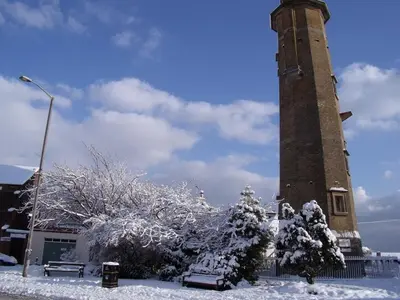 a clock tower with snow covered trees in front of it at Tidal Walk in Harwich