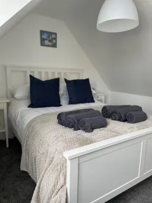 a white bed with blue pillows on top of it at Tidal Walk in Harwich