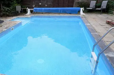 a swimming pool with blue water in a yard at Colchester Sunny Apartment with Pool and EV Car Point in Lexden