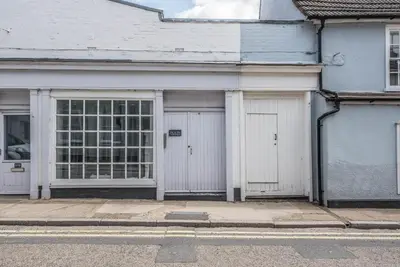 a white building with two garage doors on a street at Guildhall Street Apartment, Bury St Edmunds in Bury Saint Edmunds