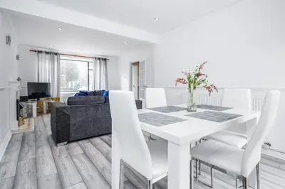 a white dining room with a white table and chairs at Bright and spacious home with free parking and garden in Mountnessing