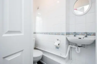 a white bathroom with a sink and a toilet at Bright and spacious home with free parking and garden in Mountnessing