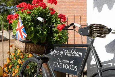 a bike with a basket full of flowers and a sign at Vine Cottage in Walsham le Willows