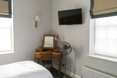 a bedroom with a television and a desk with a mirror at The Old Cannon Brewery in Bury Saint Edmunds