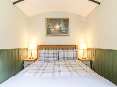 a bedroom with a bed with two lamps on both sides at The Brake Wagon at High Barn Heritage in Halstead