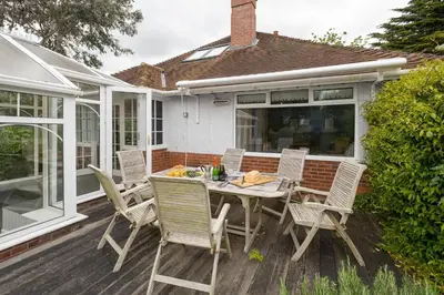 a patio with a table and chairs on a deck at Pinewood - Aldeburgh Coastal Cottages in Aldeburgh