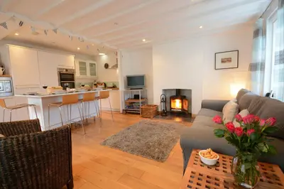 a living room with a couch and a table with flowers at Vesta Cottage, Orford in Orford