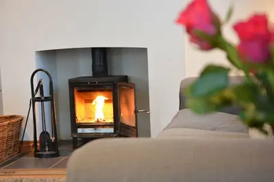 a living room with a fireplace with a person in it at Vesta Cottage, Orford in Orford