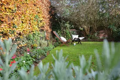 a garden with a chair sitting in the grass at Vesta Cottage, Orford in Orford