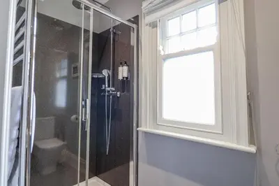 a glass shower in a bathroom with a window at Holly Lodge in Aldeburgh